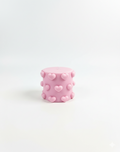 Pink cylindrical candle with heart patterns on a white background