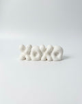 White 'XOXO' candle on a light gray background