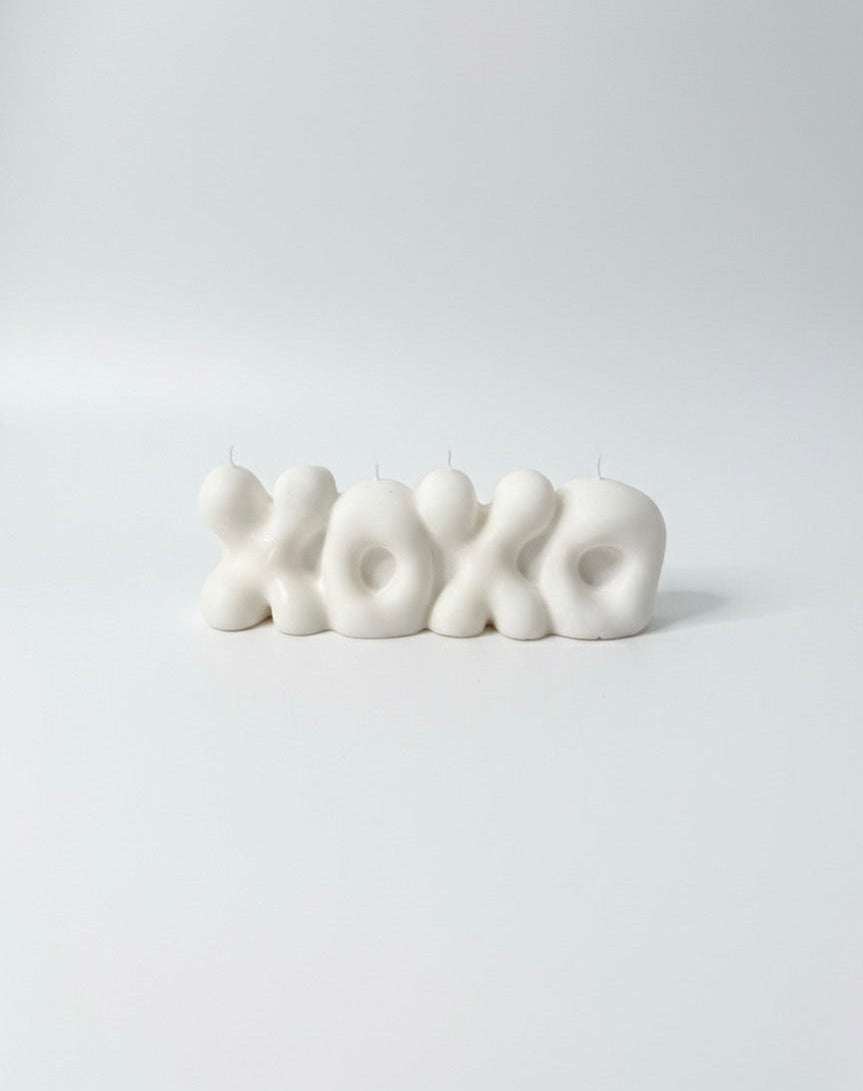White 'XOXO' candle on a light gray background