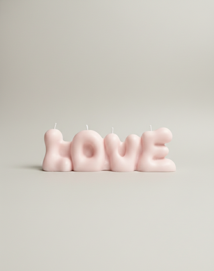 Pink 'LOVE' candle set on a light gray background