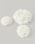 Three white peony candles on a light gray background