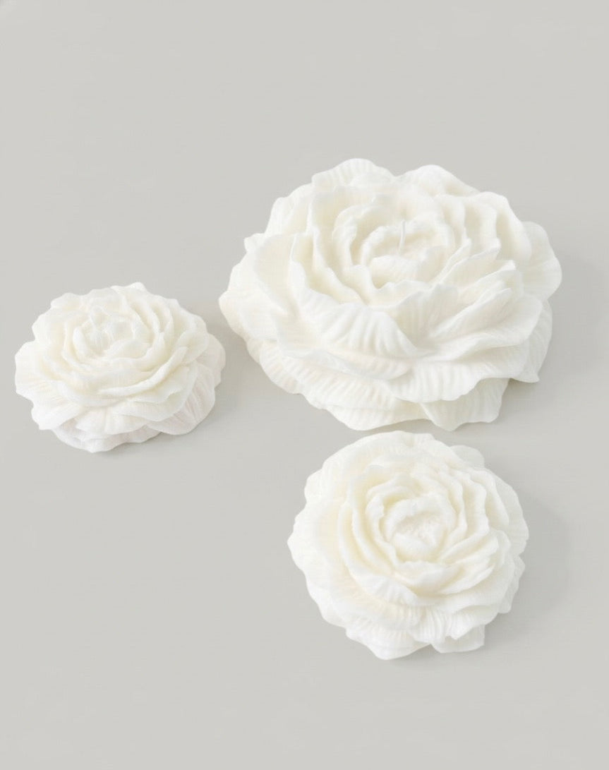 Three white peony candles on a light gray background