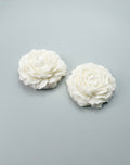 Two white peony candles on a gray background